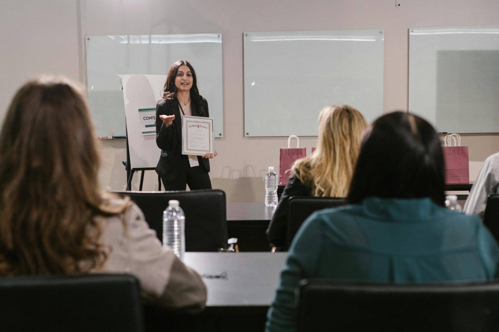 A business seminar showcasing a female presenter awarding certificates to attendees